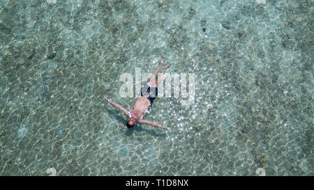 Man schwimmend auf dem Wasser im blauen Ozean. Entspannt Mann auf seine Ferien im Meer Blick von oben. Entspannen Konzeption Stockfoto
