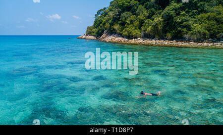 Mann allein Schnorcheln in einem tropischen Meer über Korallenriff mit klarem, blauem kristallklarem Wasser. Perhentian Island, Malaysia Stockfoto