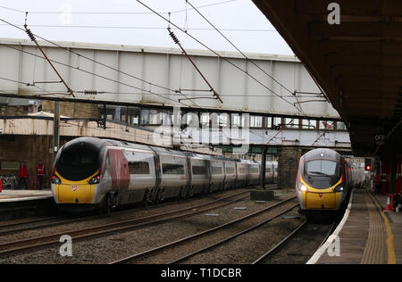 Zwei Jungfrau Westküste Pendolino elektrische Züge im Lancaster Station auf der West Coast Main Line am 21. März 2019, einem Auto und einer verlassen. Stockfoto