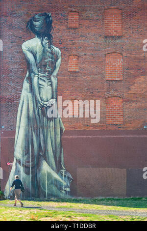 Frau geht unter einem großen Wandgemälde in der Innenstadt von Portland Oregon USA Stockfoto