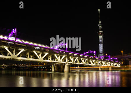 Die tobu Bahnlinie auf dem Sumida River in Downtown Tokyo ausgeführt wird beleuchtet in leuchtenden Violett leuchtet. Die Skytree leuchtet auch und eine lange Stockfoto