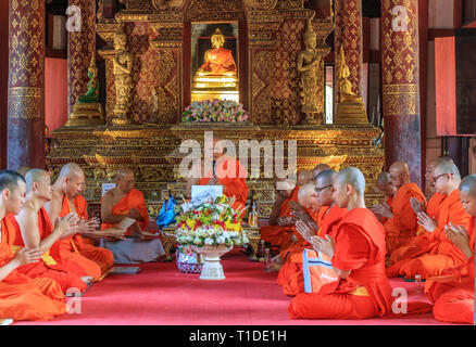 Eine Gruppe von Mönchen, die im Gebet im Innern des Wat Pra singen Tempel versammelt Stockfoto