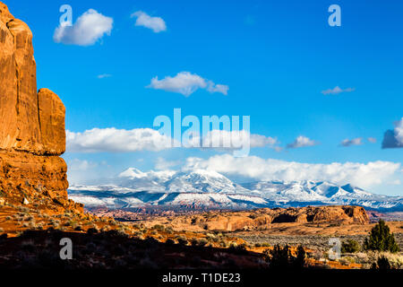 Die LaSal Mountain Range von Utah stehen über den roten Felsen der Wüste rund um Moab. Eine rote Felswand gibt Kontrast zu den schneebedeckten Gipfeln in Stockfoto