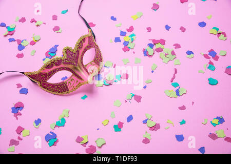 Karneval, Geburtstag. Weibliche venezianische Maske und bunte Konfetti auf rosa Hintergrund Stockfoto