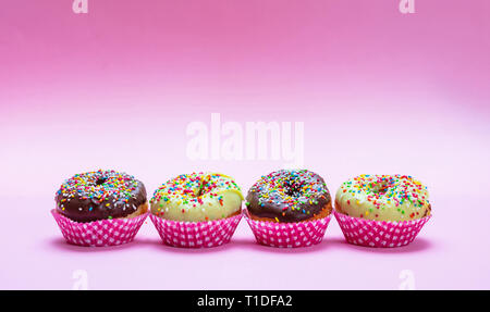 Cupcakes auf Rosa. Mini Kuchen mit Puderzucker und bunten Streuseln auf rosa Hintergrund, Detailansicht Stockfoto