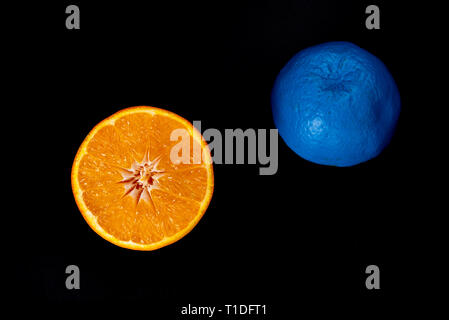 Scheiben von Blau und Orange frischem Zitrus orange Frucht auf schwarzem und gelbem Hintergrund. Still-Leben kreative Fotografie Stockfoto