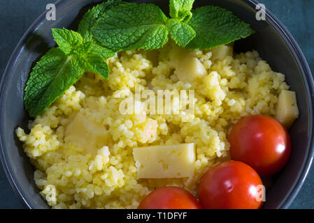 Millet Porridge mit Käse in einer Schüssel mit Tomaten und Minze. Stockfoto