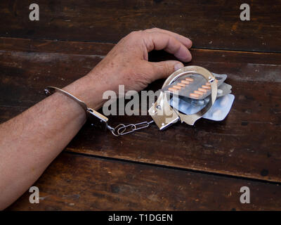 Ein Mann in Handschellen auf eine Handvoll Pillen Tabletten. Drogensucht Konzept Stockfoto