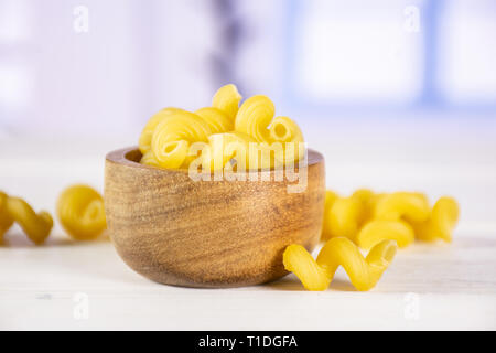 Menge ganze rohe Nudeln cavatappi mit Holzschale mit blauen Fenster im Hintergrund Stockfoto