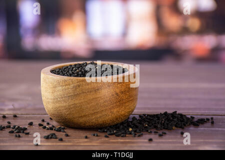 Menge ganz Schwarzkümmel Samen mit Holzschale mit Restaurant im Hintergrund Stockfoto