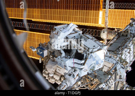 Expedition 59 NASA-Astronauten Nick Haag (Anzug mit keine Streifen) und Anne McClain (Anzug mit roten Streifen) abrufen, Batterien und Adapter Platten von einem externen Palette während eines spacewalk außerhalb der internationalen Raumstation März 22, 2019 im Erdorbit. Astronauten McClain und Haag 6-Stunden- und 39-Minuten außerhalb der Raumstation power Speicherkapazität der orbital Komplex zu aktualisieren. Stockfoto