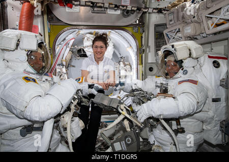 NASA-Astronaut Christina Koch, Zentrum, unterstützt Nick Haag, Links, und Anne McClain, rechts, mit ihren US-raumanzüge an der Quest Airlock, bevor Sie Ihre spacewalk beginnen die Raumstation power System März 22, 2019 im Erdorbit zu aktualisieren. Stockfoto