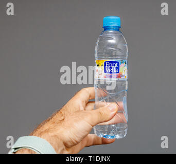 Madrid, Spanien - 11.Juni, 201*: Mann Hand, die eine PET-Flasche Font Vella Wasser bootle produziert von Danone - auf grauem Hintergrund Stockfoto