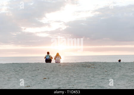 Zwei Leute, die schönen und heiteren Sonnenuntergang über dem Meer Horizont beim Sitzen im Sand am tropischen Strand Stockfoto