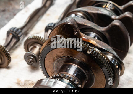 Nahaufnahme eines Auto Kurbelwelle und Welle mit Getriebe und Lager für den Austausch auf einer Werkbank in einem Fahrzeug Werkstatt entfernt. Auto Service Industrie. Stockfoto