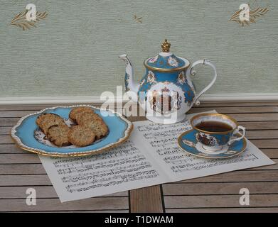 Englisch Teetasse mit Untertasse, Teekanne und einem Kuchen Teller mit Keksen, Fine Bone China Porzellan, auf einem Blatt von Musik Stockfoto
