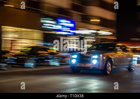 Verschwommenes Bild von sich schnell bewegenden Rolls-Royce Phantom Limousine auf einer Londoner Straße bei Nacht Stockfoto