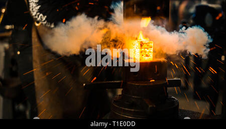 Schlosser schlägt das heiße Bügeleisen um die gewünschte Form zu geben. Stockfoto