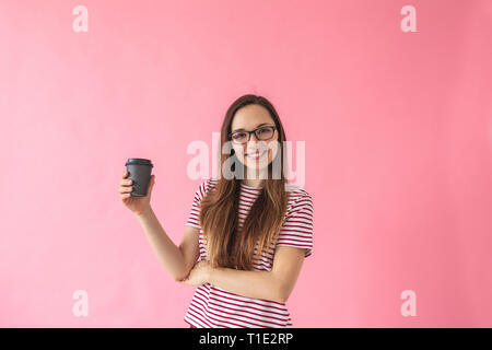 Schönen Lächeln positive Mädchen trinkt Kaffee auf einem rosa Hintergrund. Kaffeepause. Stockfoto