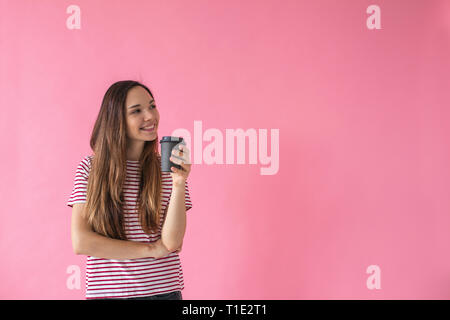 Schönen Lächeln positive Mädchen trinkt Kaffee auf einem rosa Hintergrund. Kaffeepause. Stockfoto