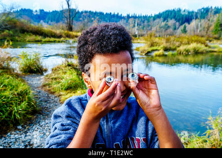 Junge mit den Augen einer toten Lachs in die Laichgebiete in der Stabkirche Fluss hinter dem Ruskin Damm Hayward See an der Mission, BC, Kanada Stockfoto