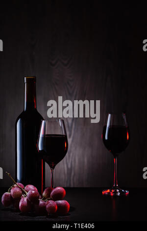 Rotwein in Glas und Flasche mit Weintraube Stockfoto