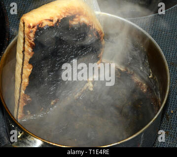 Topf mit Reis in einem gebrannten Kochen Tasche, das Ergebnis von kochendem Wasser, ist es immer noch rauchen. Stockfoto
