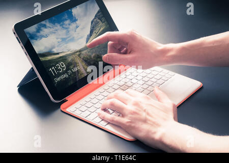 Männliche Hände und weiß orange Convertible Notebook Stockfoto