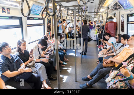 Passenegers über ihre mobilen Geräte, während Sie von Stadt U-Bahn in Bangkok, Thailand pendeln Stockfoto