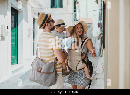 Eine junge Familie mit 2 Kleinkind Kinder gehen in der Stadt im Sommerurlaub. Stockfoto