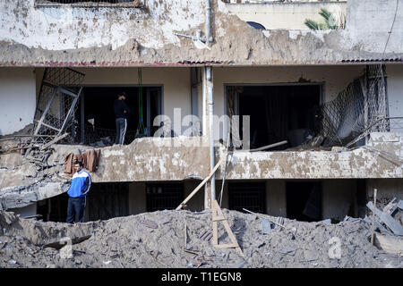 Gaza, Palästina. 26 Mär, 2019. Ein Mann auf der Vorderseite eines zerstörten Gebäude nach einem israelischen Luftangriff in Gaza. israelische Luftangriffe auf den Gazastreifen an mehreren Stellen über die Nacht, die als Reaktion auf eine seltene Fernverkehr Raketenangriff aus dem palästinensischen Enklave, die ein Haus in Tel Aviv getroffen und verletzt 7 Person am Montag wurden getroffen. Credit: Mohamed Zarandah/SOPA Images/ZUMA Draht/Alamy leben Nachrichten Stockfoto