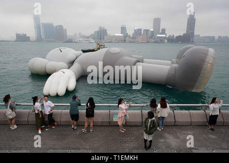 Hongkong, China. 26 Mär, 2019. Besucher versammelt sich vor der KAWS: urlaub Installation auf Anzeige in Hong Kongs Victoria Harbour. Die kaws: Urlaub erweiterten Struktur durch amerikanische Künstler Brian Donnelly, auch bekannt als KAWS, wird auf dem Display werden bis zum 31. März 2019. Quelle: Christopher Jue/ZUMA Draht/Alamy leben Nachrichten Stockfoto