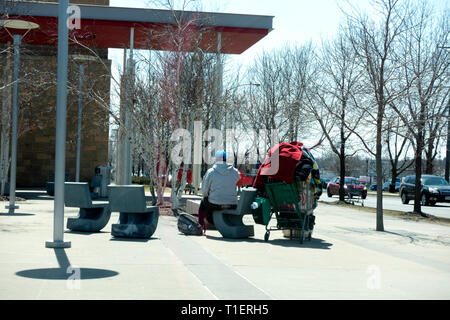 Obdachlosen Mann sitzt auf der Terrasse des Ziels mit einem Korb hoch aufgetürmt, wahrscheinlich mit all seinen Besitz. St. Paul Minnesota MN USA Stockfoto