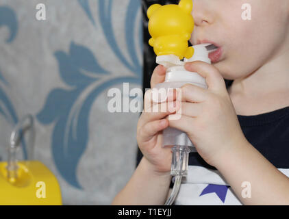 Das Kind macht einatmen. Der Junge hält in seiner Hand ein Inhalationsgerät für die Behandlung von Atemwegserkrankungen. Einatmen. Die Behandlung von Kindern. Die Stockfoto