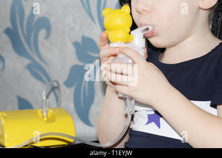 Das Kind macht einatmen. Der Junge hält in seiner Hand ein Inhalationsgerät für die Behandlung von Atemwegserkrankungen. Einatmen. Die Behandlung von Kindern. Die Stockfoto