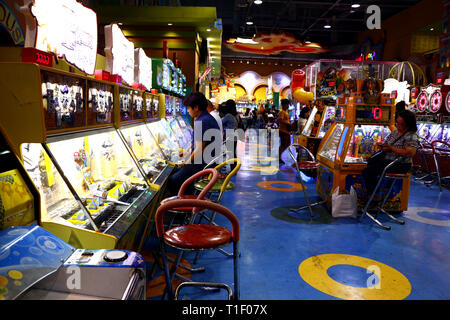 QUEZON CITY, Philippinen - 24. MÄRZ 2019: Kunden versuchen, verschiedene Video- und Arcade Spiele in eine Arkade mit einem kommerziellen Zentrum. Stockfoto