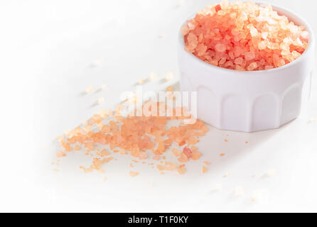 Große Kristalle rosa Himalaya Salz in Keramik Glas. Weißer Hintergrund. Stockfoto