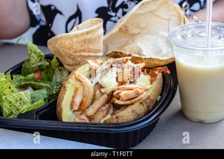 Mahlzeit mit doppelt gebackene Kartoffeln mit Huhn und Käse grüner Salat und Fladenbrot serviert. Gesund essen oder fast food Konzept. Stockfoto