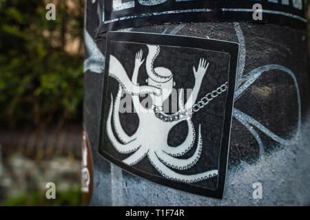 Bizarre Graffiti-Nahaufnahme von Schwarz-Weiß-Halb-Mensch-Oktopus-Kunstaufkleber an einem Straßenpfosten Stockfoto