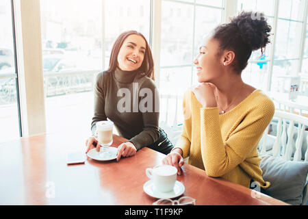 Zwei beste Freunde sitzen im Cafe und eine gute Zeit zusammen verbringen. Mädchen trinken einige Latte und genießen Sie Ihre Unterhaltung. Close Up. Stockfoto