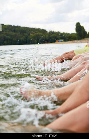 Senioren Spritzen mit ihren Füßen in den See und Spritzen mit Wasser im Sommer Stockfoto