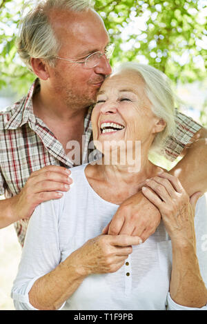 Älterer Mann küsst liebevoll seine lachenden Frau im Sommer in der Natur Stockfoto