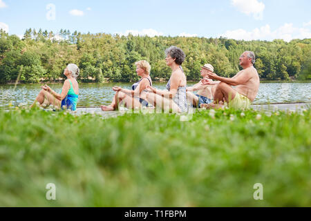 Gruppe von Senioren Yoga Übungen auf dem See im Sommer Stockfoto