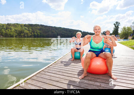 Vital älterer Frauen in zurück Training mit gym ball in der Reha auf dem See Stockfoto