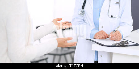 Unbekannte Frau Arzt und Patientin etwas diskutieren beim Stehen in der Nähe der Rezeption in der Notaufnahme im Krankenhaus. Arzt bei der Arbeit in der Klinik Stockfoto
