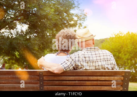 Glückliches Paar von Senioren in Liebe sitzt auf einer Parkbank im Herbst Stockfoto