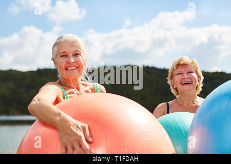 Zwei glückliche älterer Frauen mit Gymnastikball im rehab Kurs im Sommer am See Stockfoto
