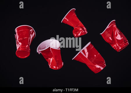 Blick von oben auf die hellen und farbenfrohen roten Plastikbecher isoliert auf Schwarz mit Kopie Raum Stockfoto