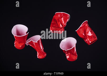 Blick von oben auf die hellen und farbenfrohen roten Plastikbecher isoliert auf Schwarz mit Kopie Raum Stockfoto