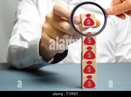 Geschäftsmann entfernt einen Cube mit einem Bild von Dollar. Sabotage der Wirtschaft. Der kapitalabfluss. Finanzkrise. Konkurs. Druck auf kleine busine Stockfoto